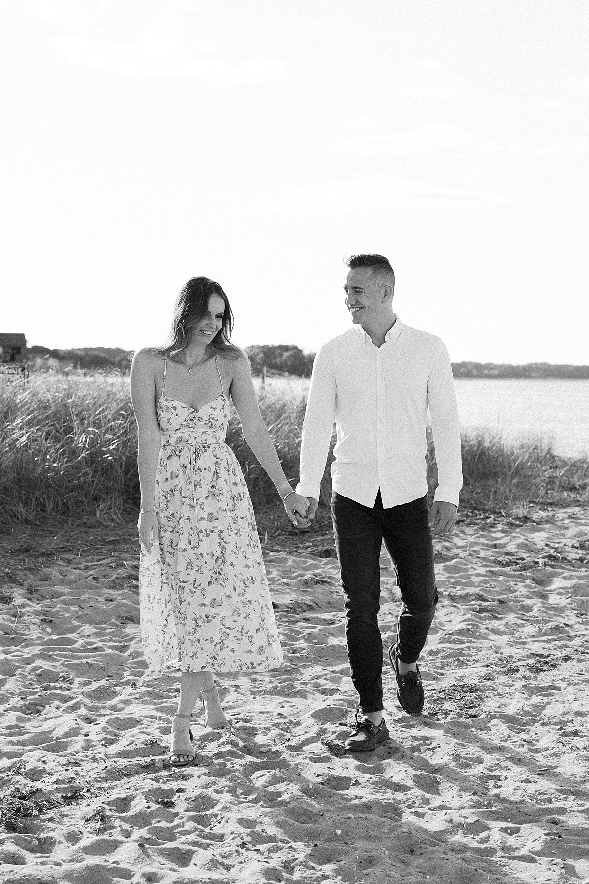Black and white photo of a couple walking on the beach 