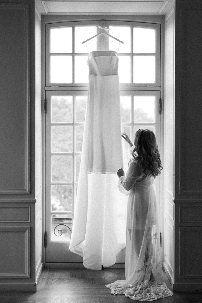 Black and white photo of wedding gown hanging in the window at Glen Manor House