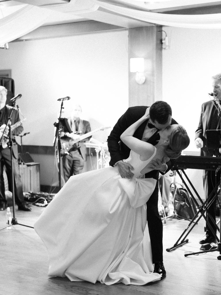 Bride and groom kissing during first dance in front of the band
