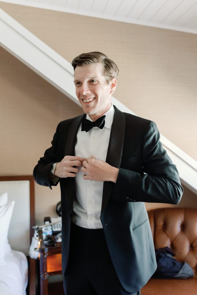 groom putting on his tux for spring wedding in New England 
