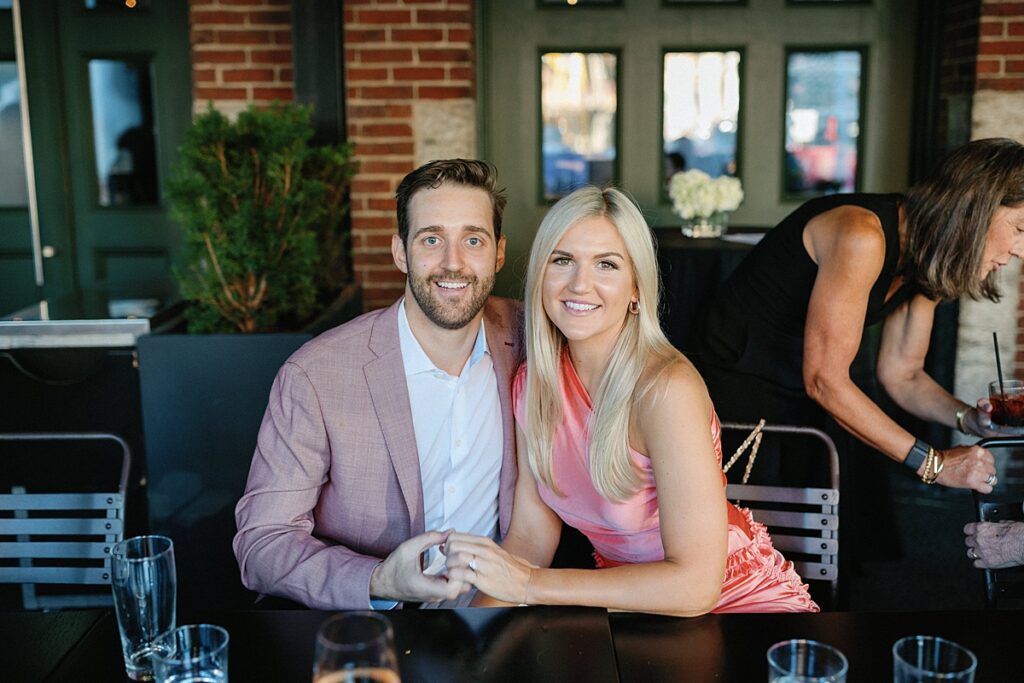 Couple sitting at a table, smiling and looking at camera