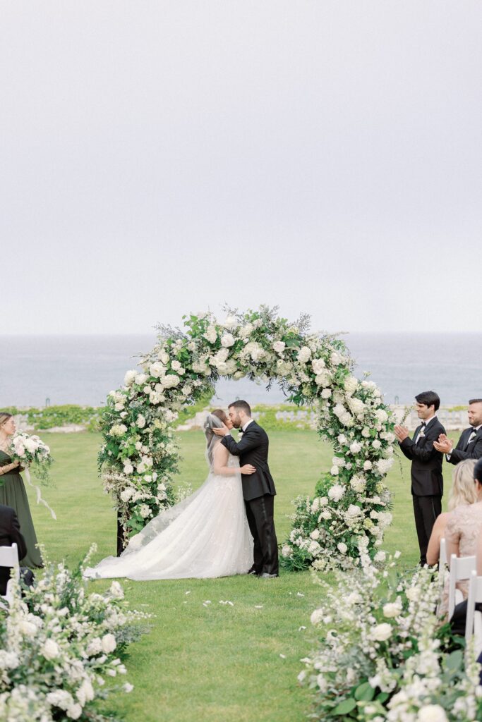 Bride and groom first kiss during outdoor ceremony at Rosecliff 