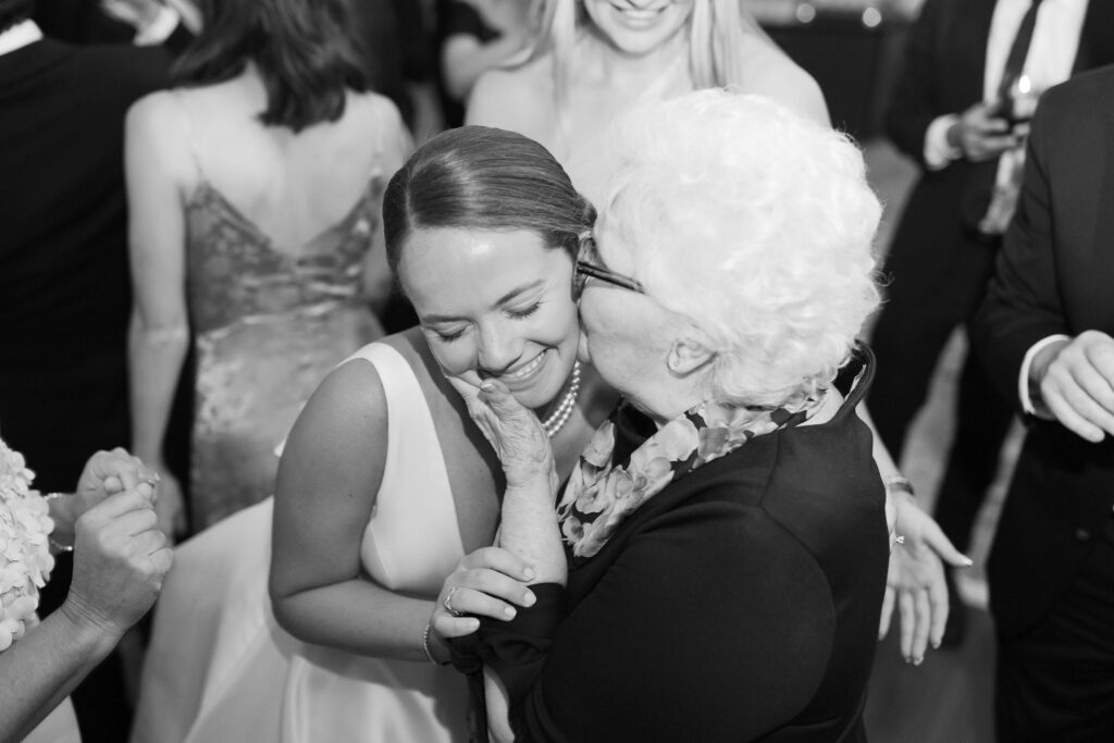 Candid black and white photo of bride and grandmother at wedding reception 