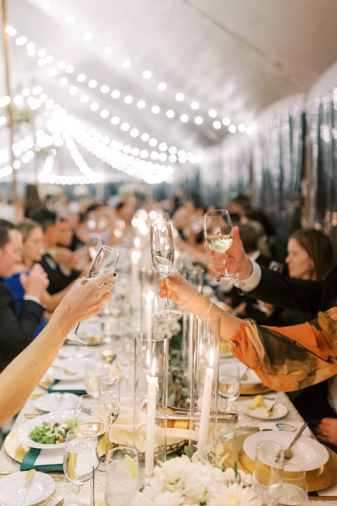 Wedding guests cheersing to bride and groom during tented wedding reception 