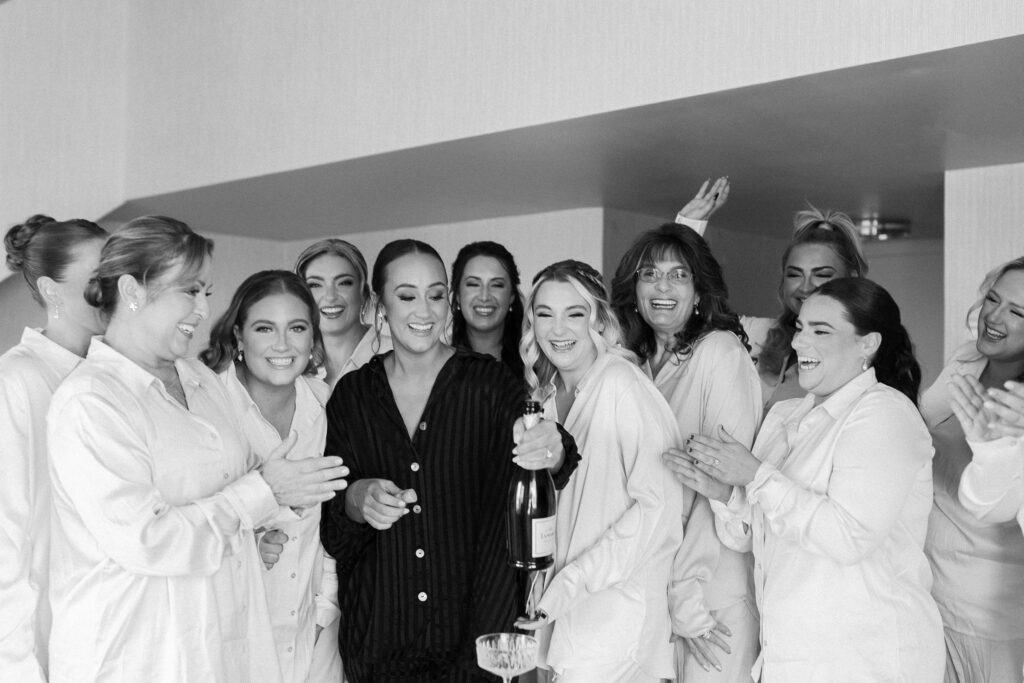 Bride and bridesmaids popping champagne while getting ready for Newport wedding