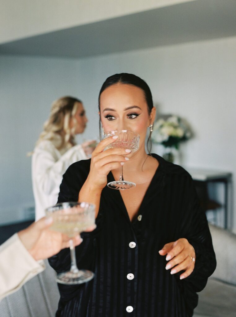 Bride sipping champagne while getting ready for Newport wedding