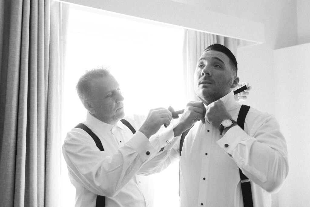 Groom putting on bow tie with the help of his dad