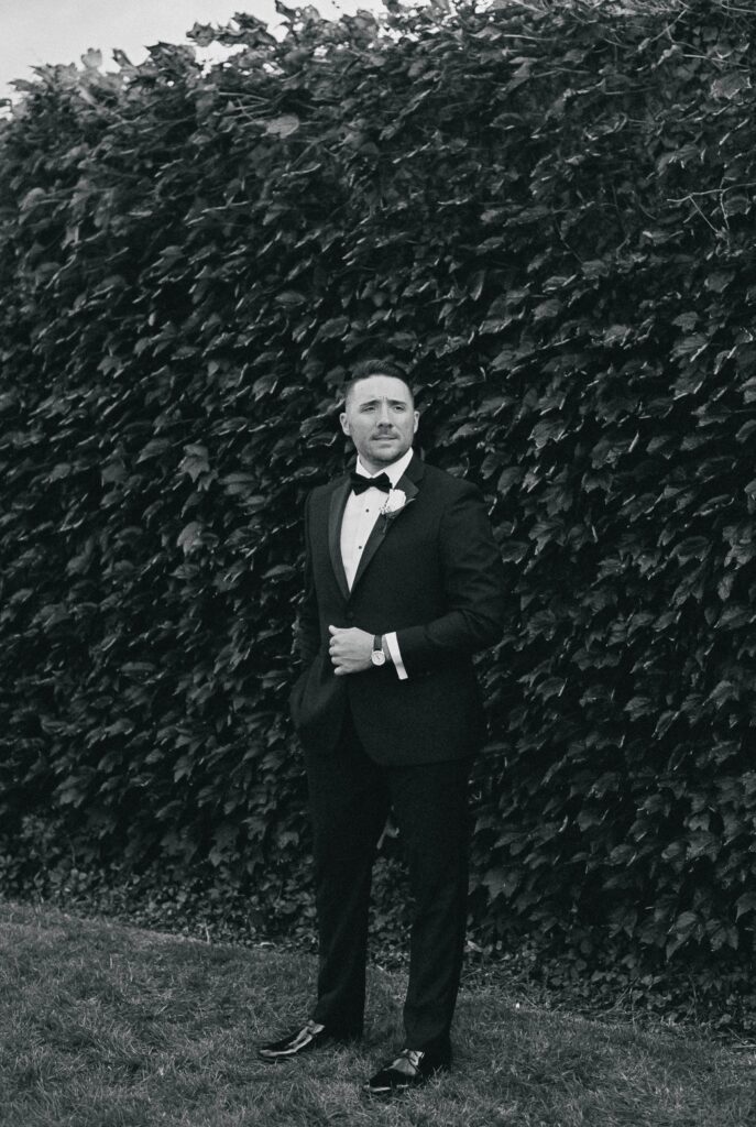 Black and white portrait of Groom in front of Ivy wall at Belle Mer