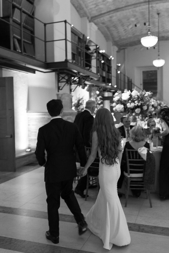 Black and white photo of bride and groom holding hands during Boston wedding reception