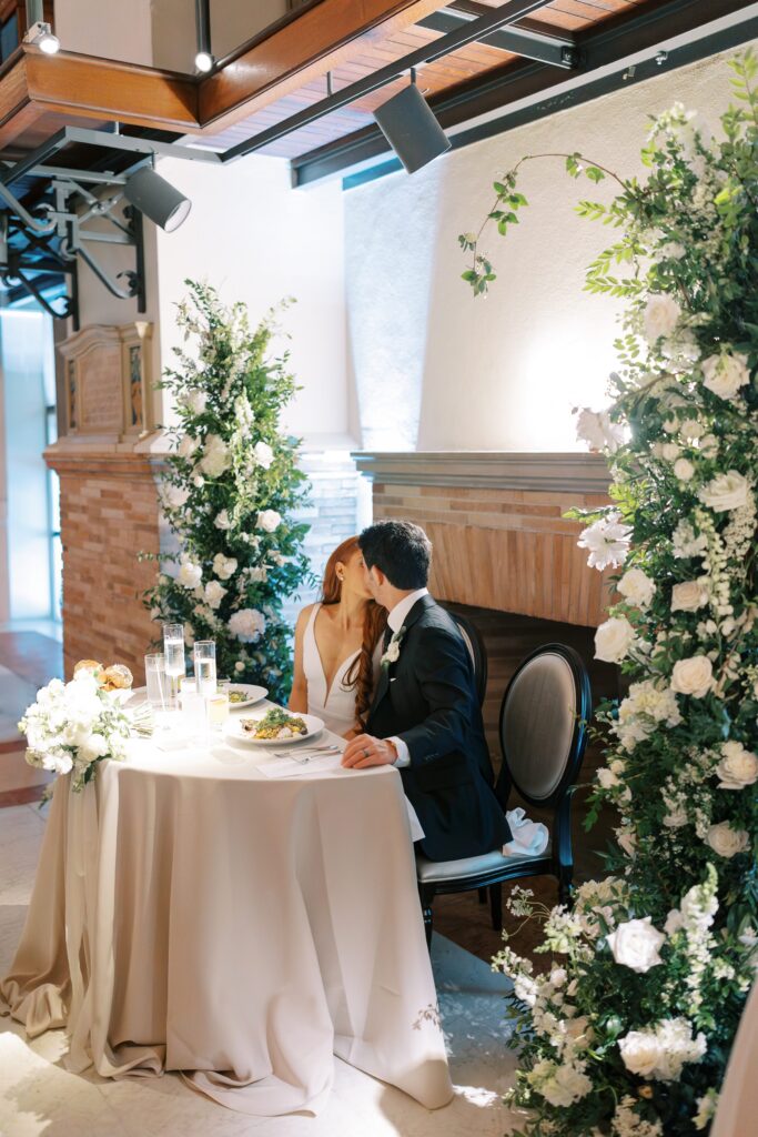 Bride and groom kiss at their sweetheart table 