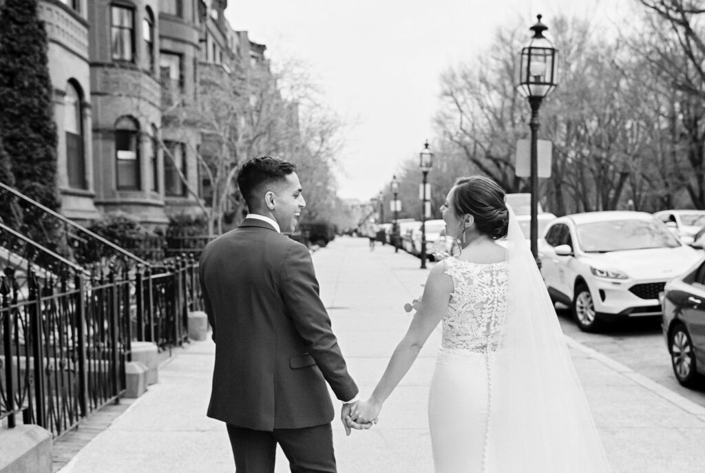 Bride and groom holding hands while walking the streets of Boston capturing wedding portraits 
