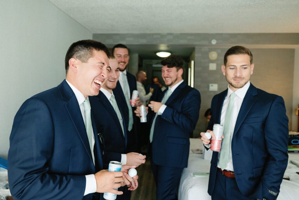 Groom and groomsmen laughing while getting ready for wedding