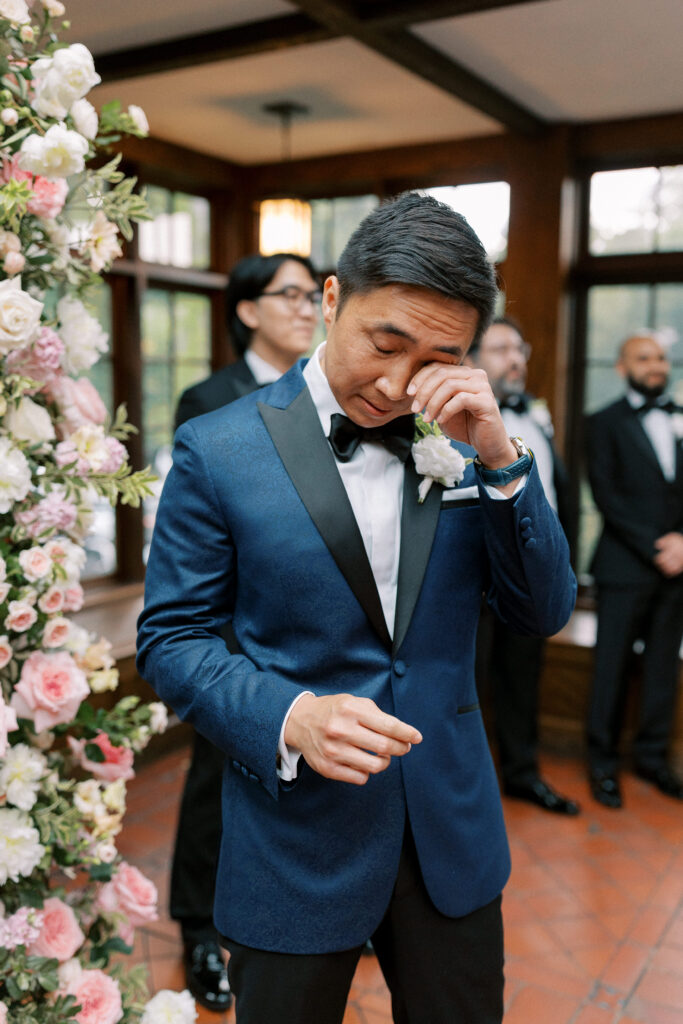 Groom wiping tear during ceremony at Willowdale Estate