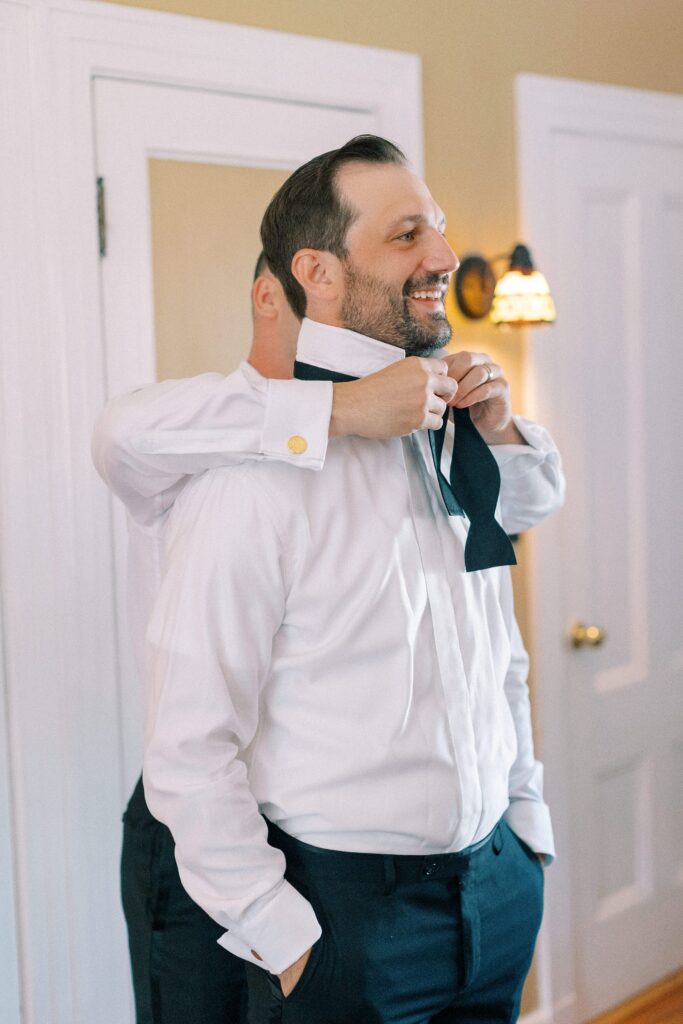 Groom getting help putting on a bowtie for Willowdale Estate wedding