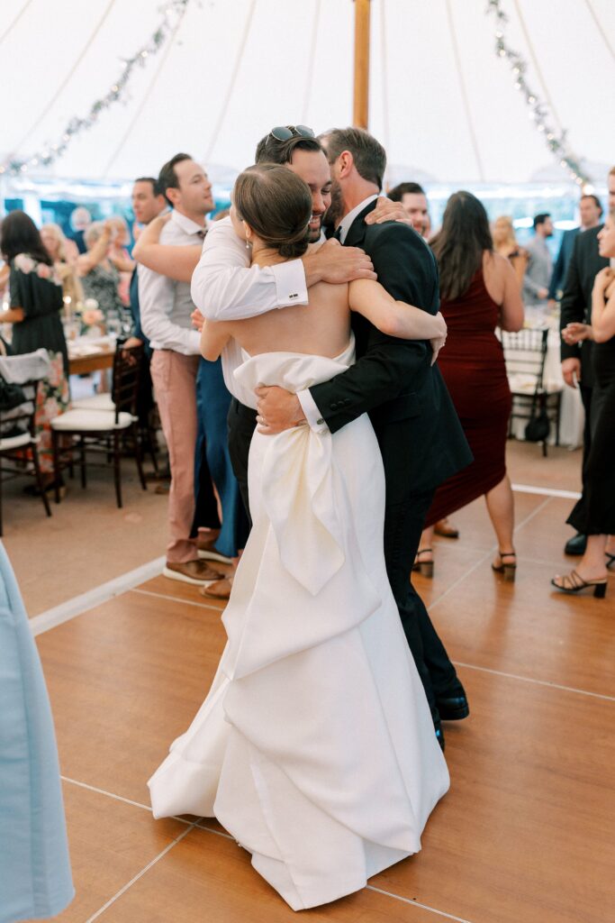 Candid photo of bride and groom hugging friend