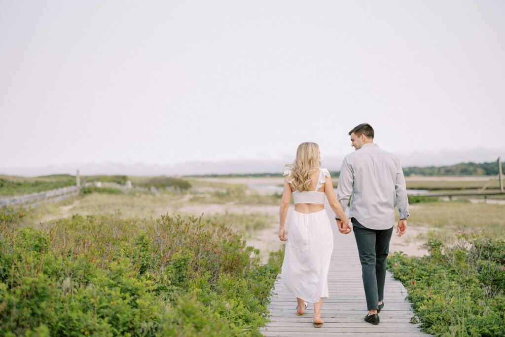 Couple holding hands while walking on the boardwalk during engagement photos