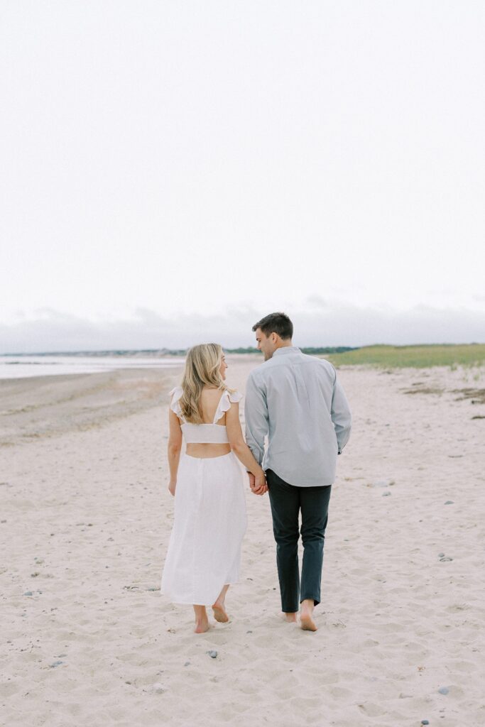 Beach Engagement Photography in Sandwich, MA with couple walking hand in hand