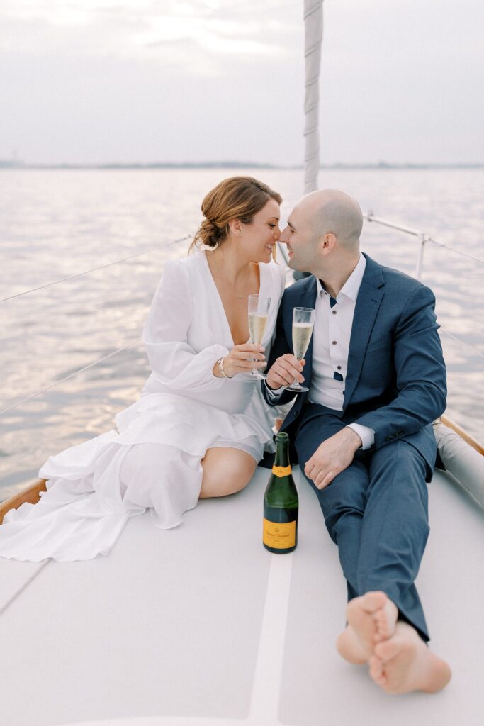 Sailboat Engagement Session off the coast of New England with couple drinking champagne 