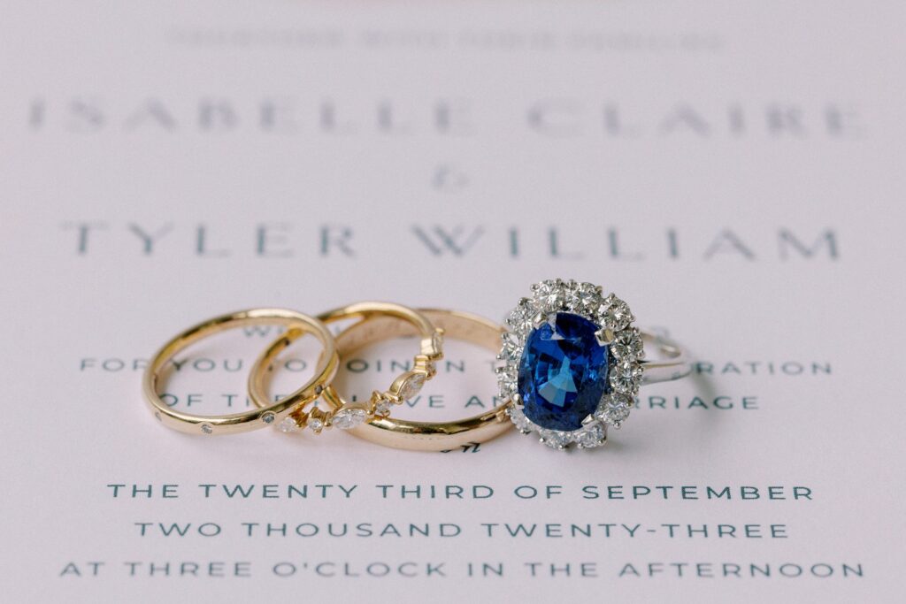 Sapphire engagement ring and wedding bands detail photography on wedding stationery 