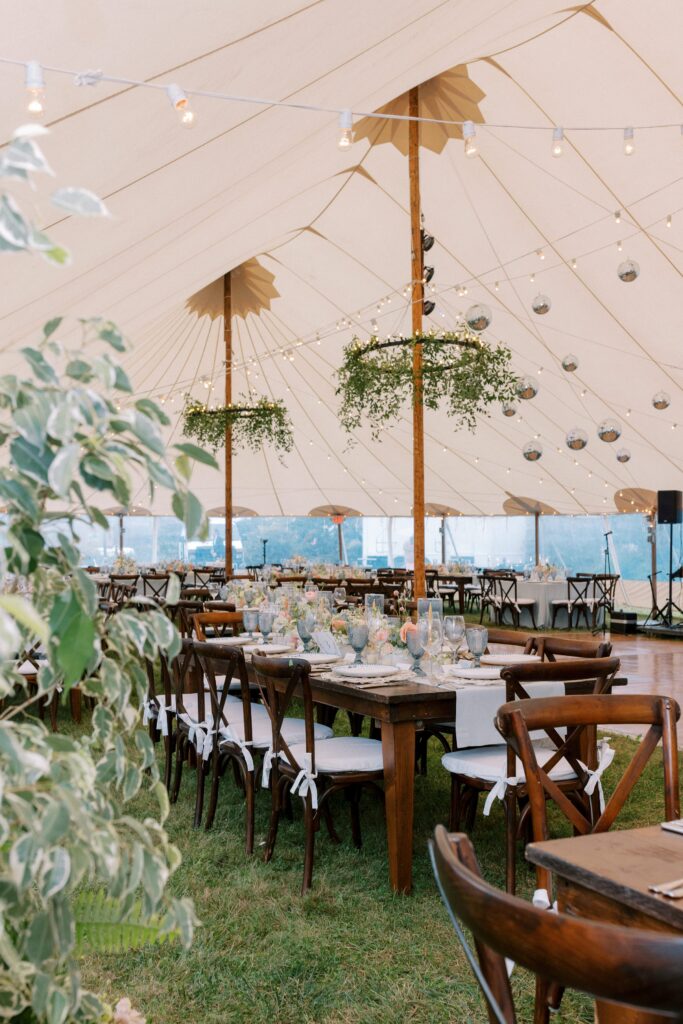 Sailcloth tent with hanging greenery and farmhouse tables for Martha's Vineyard wedding