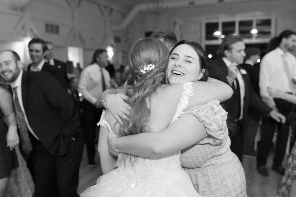 Bride hugging her friend on the dance floor 